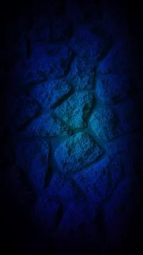 Dark grainy stone wall with a deep blue glow at the center, creating a calm.. Stock Photos