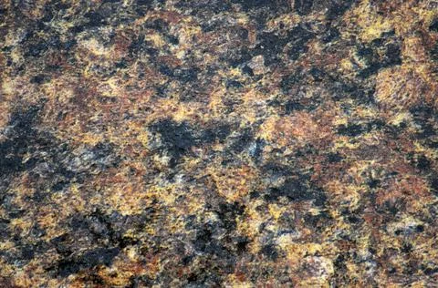 Dark granite, a flat, polished surface of natural stone with brown patches. Stock Photos