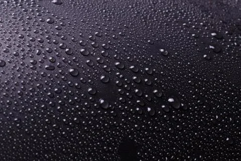 Dark gray background with white light and not evenly sprayed drops of water a Stock Photos