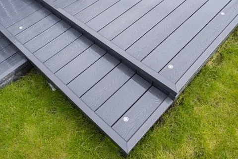 Dark gray deck planks lie on green grass 스톡 사진