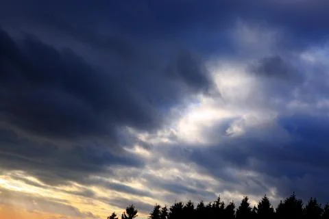 Dark gray dramatic sky with large clouds and sunlight. Stock Photos