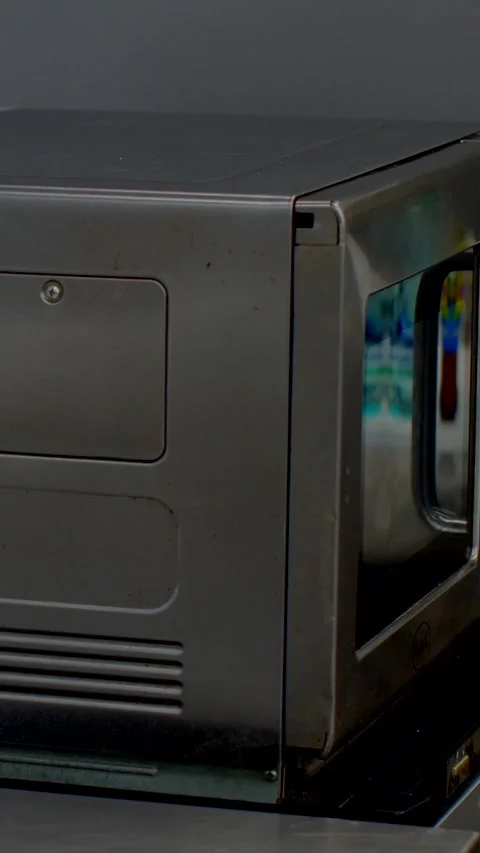 Dark gray metal appliance side corner with access hatch and tubular door handle Stock Footage 345601279