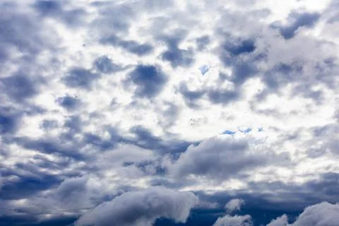 Dark gray rain clouds close sun in dark blue sky Stock Photos