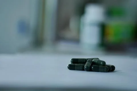 Dark green capsules on a white surface, representing medicine, health 스톡 사진