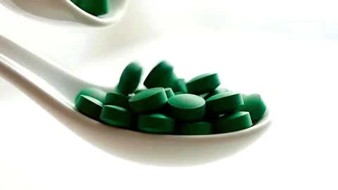 Dark green, round supplement pills (like spirulina or chlorella) falling. Stock Footage 314429256