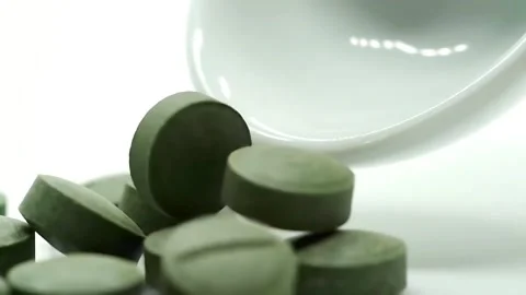 Dark green, round supplement pills (like spirulina or chlorella) falling. Stock Footage 314429259