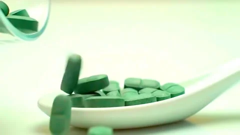 Dark green, round supplement pills (like spirulina or chlorella) falling. Stock Footage 314429273