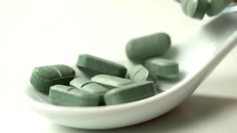 Dark green, round supplement pills (like spirulina or chlorella) falling. Stock Footage 314429275