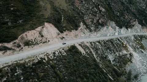 Dark grey car drives through narrow road in the mountains. Drone footage Stock Footage 166061011