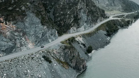 Dark grey car drives through narrow road in the mountains. Drone footage Stock Footage 166061236