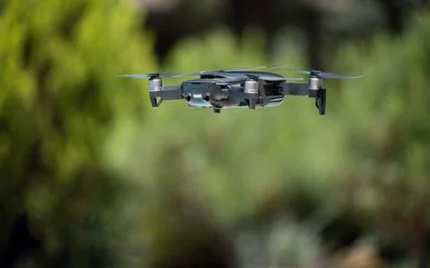 Dark grey drone flying over a green background Stock Photos