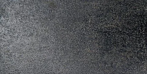 Dark grey rough stone surface texture background, close up grainy charcoal. Stock Photos
