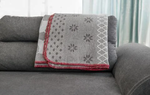 Dark grey sofa with a folded patterned blanket on top Stock Photos