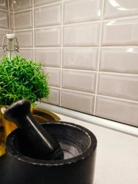 A dark grey stone mortar on the kitchen table against a background of white t Stock Photos