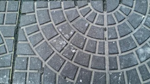 Dark grey stone paving blocks arranged in curved circular geometric pattern Stock Photos