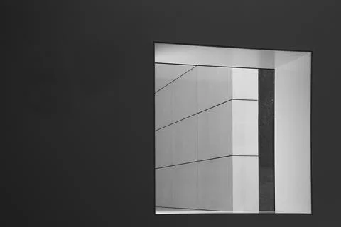A dark grey wall with a window leading to a white wall with diagonal lines 库存照片