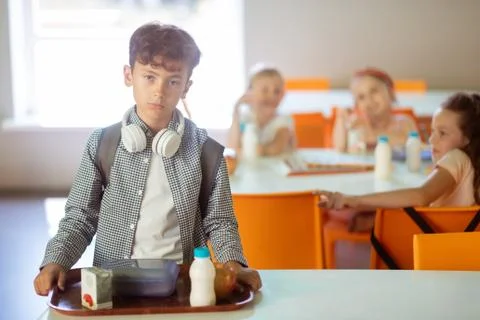 Dark-haired boy feeling like outcast while eating alone in canteen Fotos Stock