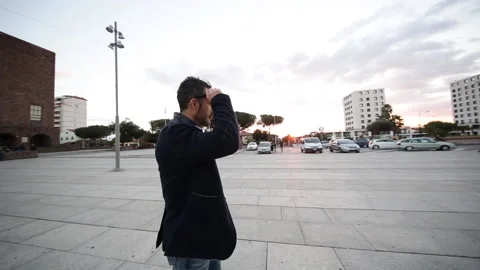 Dark-haired boy with jacket , wanders around a square in the center of a city Stock Footage 132617524
