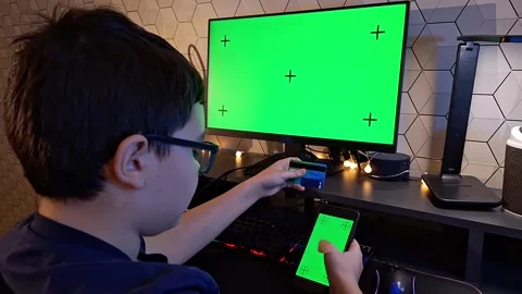 A dark- haired boy scroll a smartphone and holds a bank card, sitting in front Stock Footage 271082286