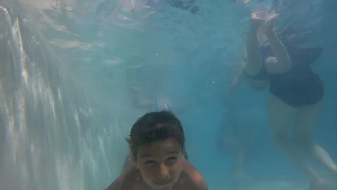 The dark-haired boy slowly dives under the water Stock Footage 246411059