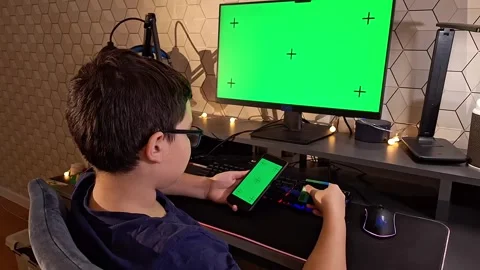 A dark- haired boy uses a smartphone and holds a bank card, sitting in front of Stock Footage 273742705