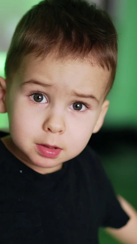 Dark-haired Caucasian boy in black t-shirt sitting on the chair. Mom's hand Stock Footage 333472673