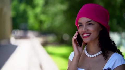 A dark-haired curly-haired young girl walking through a green summer Park. She 動画素材 134842405
