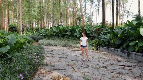 A dark-haired girl stands on the path of a city park after a typhoon. Stock Footage 115563548