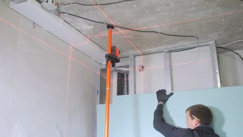 Dark haired handyman fixes blue plasterboard on wall Stock Footage 108581739