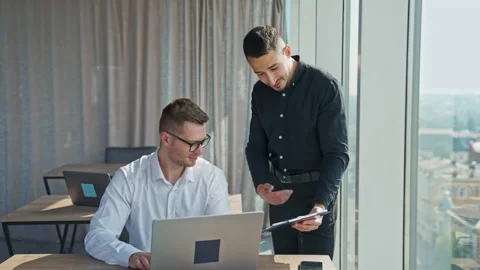 Dark-haired man in black clothes showing documents to his colleagues sitting  Stock Footage 217425658