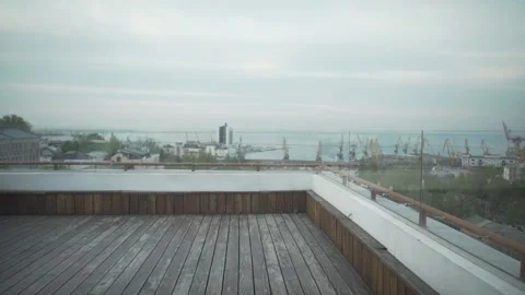 Dark haired man in casual clothes with journal in hand walking on wood rooftop l Video stock 132675471