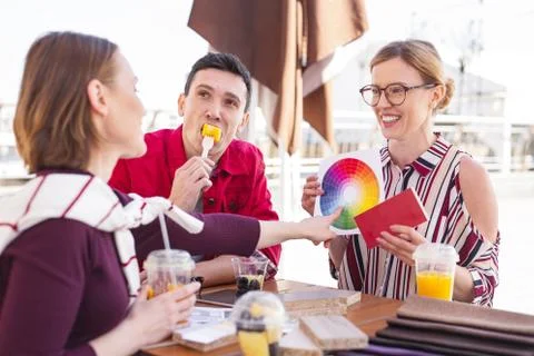 Dark-haired man eating mango sitting outside with friends Stock Photos