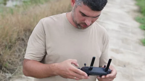 A dark haired man holds a drone remote control in his hands. Stock Footage 321728399