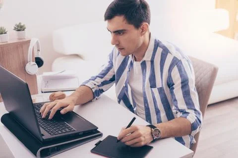 Dark-haired man Illustrator draws on graphic tablet, freelancer, remote work  Stock Photos
