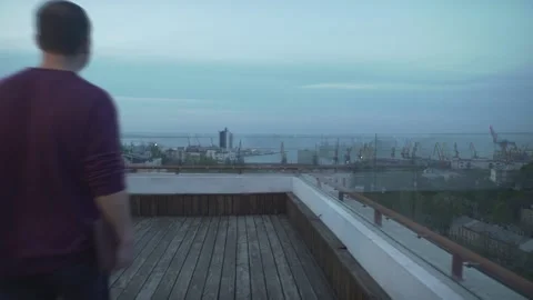 Dark haired man with journal in hand in casual clothes looking at harbor seascap Stock Footage 132675506