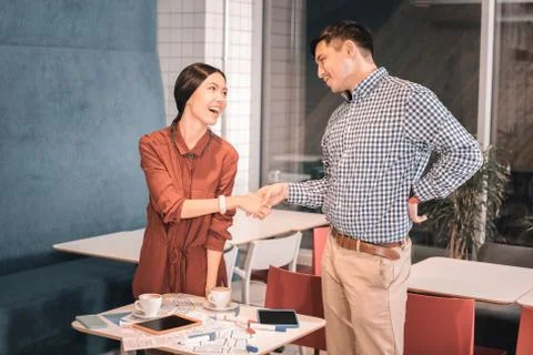 Dark-haired man shaking hand of his business partner meeting her Stock Photos