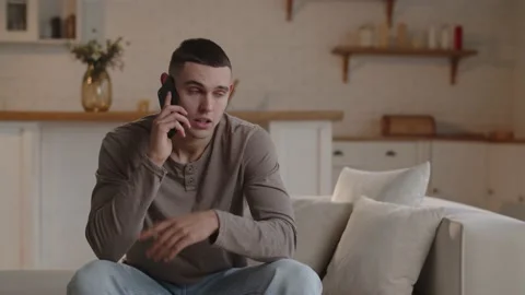 A dark-haired man sitting in a home office is discussing something on the Stock Footage 234496612