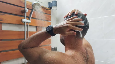 A dark haired man soaping his hair while standing in the shower. Stock Footage 318165045