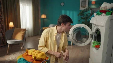 Dark-haired man standing in the room, unloading the washing machine, excited and Stock Footage 252388425