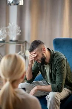Dark-haired man talking about depression to psychologist Stock Photos