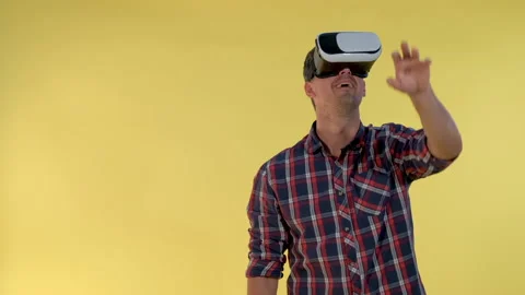 Dark-haired man using virtual reality glasses while standing against yellow Video stock 152451056