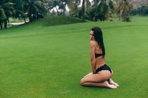 Dark-haired model with a round beautiful booty sitting in a swimsuit on her Stock Photos