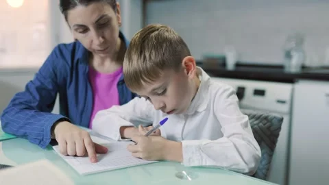 Dark-haired mother helping her young son with homework at the kitchen table. Stock Footage 345916991