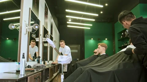 Dark haired stylist trims lying in armchair customer beard 스톡 동영상 142679404