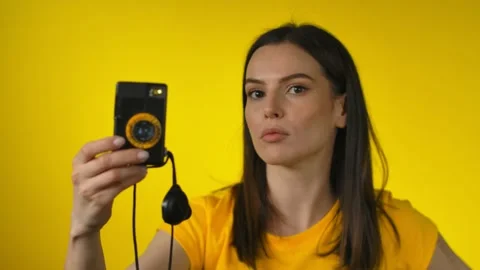 Dark-haired woman is using a retro camera for shooting a picture in a mirror Stock Footage 161066875