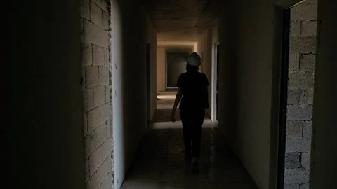 Dark hallway of brick building under construction, female worker going through Stock Footage 248468573