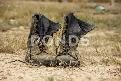 Dark high leather combat boots stand in the steppe. Stock Photos