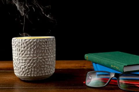 A dark image with stack of books, reading glasses and stone candle holder on  Stock Photos