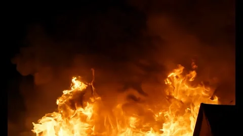A dark, intense fire with thick, orange flames and dark smoke against a black ba Stock Footage 282653236