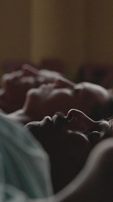 Dark intimate close-up of long-haired man resting in savasana, soft light Stock-Footage 347704244